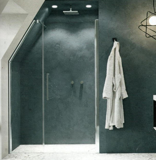 Semi-frameless shower enclosure comprising a hinged door with inline angled fixed panel.